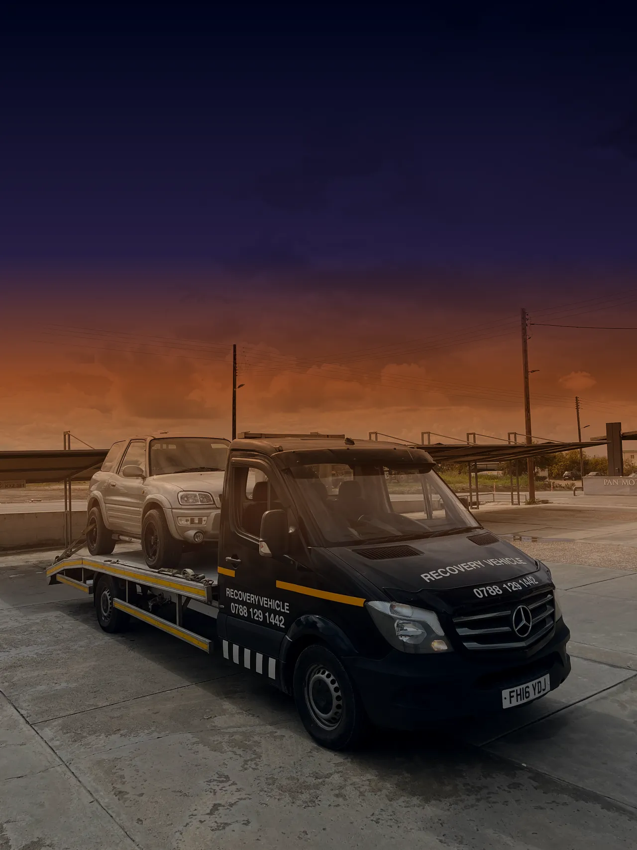 S.Prestige Mercedes Sprinter flat-bed recovery truck loaded with a vehicle at dusk